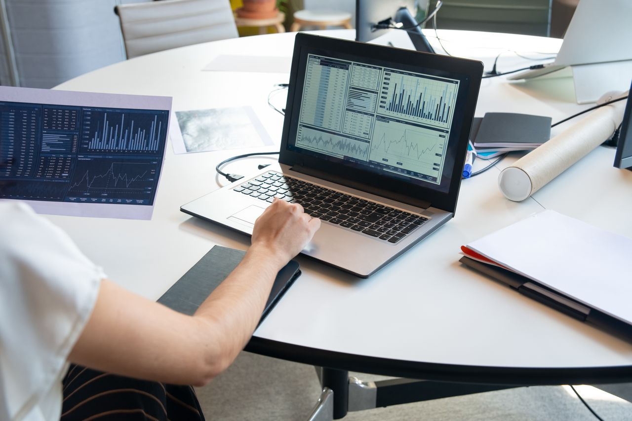 cta-bg Business person evaluating financial charts on a laptop in a modern office setting.